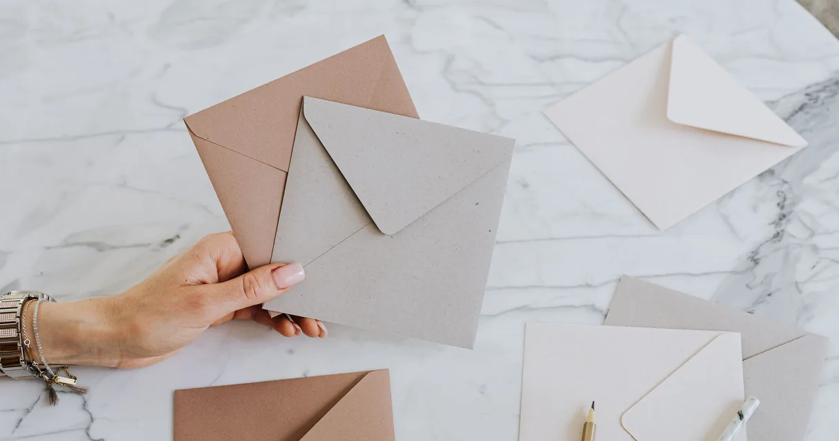 Envelopes de papel em tons neutros sobre uma mesa de mármore, ilustrando como fazer um envelope com folha A4