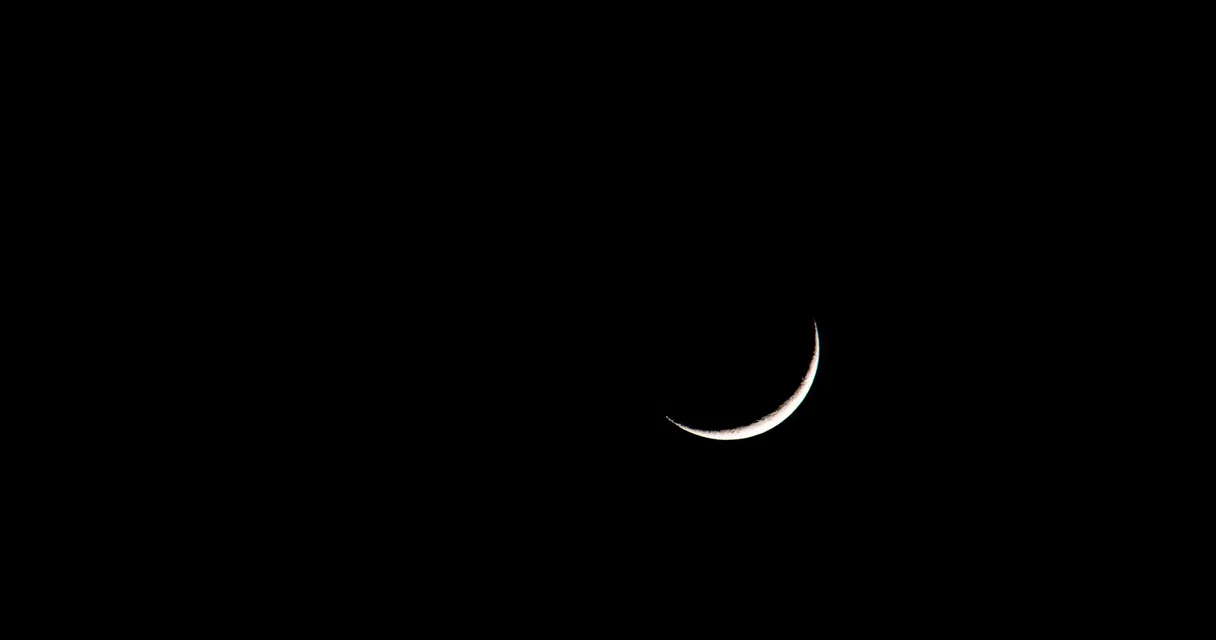 Lua crescente fina no céu escuro, ilustrando como tirar foto da lua